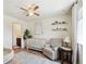 Sunlit Bedroom featuring crib, cozy chair, wood-look floors, and modern decor at 16188 Elizabeth St, Thornton, CO 80602