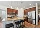 Kitchen with island and seating, stainless steel appliances, and dark wood cabinets at 16188 Elizabeth St, Thornton, CO 80602