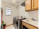 Functional laundry room with modern washer and dryer, sink, and storage cabinets at 11851 Elm Dr, Thornton, CO 80233