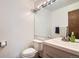 Bathroom featuring a sleek vanity with modern fixtures, a toilet, and a large mirror with vanity lighting at 9957 Grove Way # F, Westminster, CO 80031