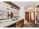 Kitchen view with tile counters, wood cabinets, view to a living room and a door to the utility area at 9957 Grove Way # F, Westminster, CO 80031
