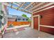 Back patio with a pergola, a red wood paneled wall, stone floor and wood fence at 2502 Alton St, Denver, CO 80238