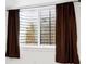Basement window with safety bars and brown curtains at 2502 Alton St, Denver, CO 80238