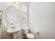 Bright powder room featuring pedestal sink, oval mirror, plantation shutters, and neutral walls at 2502 Alton St, Denver, CO 80238