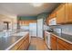 Well-lit kitchen with oak cabinets, modern appliances, tiled floor, and a double basin sink at 22725 E Long Dr, Aurora, CO 80016