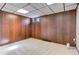 Finished basement with carpet floor, drop ceiling, and wood paneled accent wall at 3561 Kalispell St, Aurora, CO 80011
