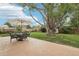 Backyard featuring a patio dining area, a lush lawn, a fence, and a large tree at 7075 Welch Ct, Arvada, CO 80004