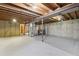 Unfinished basement with exposed ceiling beams, concrete walls, and utility hookups, offering potential for customization at 7075 Welch Ct, Arvada, CO 80004