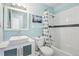 Cozy bathroom with bright, clean, white tiled walls, modern vanity, matching framed mirror, and a shower with updated fixtures at 7075 Welch Ct, Arvada, CO 80004
