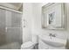 Clean bathroom with a shower, a vanity, and a decorative mirror reflecting natural light at 7075 Welch Ct, Arvada, CO 80004