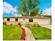 Charming single-story home with a well-manicured lawn, rock pathway, and mature trees under a sunny blue sky at 7075 Welch Ct, Arvada, CO 80004