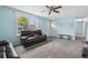 Bright living room featuring soft blue walls, a ceiling fan, and a cozy, oversized leather reclining sofa at 7075 Welch Ct, Arvada, CO 80004