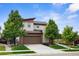 Charming two-story home with a brown and beige exterior, a well-manicured lawn, mature trees, and a two car garage at 17258 E 109Th Ave, Commerce City, CO 80022