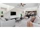 Open-concept living room with a ceiling fan, comfortable seating, dark hardwood floors, and flows into a modern kitchen at 17258 E 109Th Ave, Commerce City, CO 80022