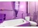 Bathroom with vibrant purple walls, a white bathtub, and matching toilet at 2410 W 36Th Ave, Denver, CO 80211