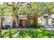 Charming two-story brick home with a cozy front porch and lush green lawn, shaded by mature trees at 2410 W 36Th Ave, Denver, CO 80211