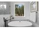 Relaxing bathroom with soaking tub, marble tile, and forest views at 8006 S Settlers Dr, Morrison, CO 80465