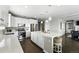 Open kitchen with white cabinets, stainless appliances, large island with seating open to the living space at 12554 Hudson Ct, Thornton, CO 80241