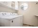 Functional laundry room featuring appliances, overhead cabinets, and a round window at 4032 S Lisbon Way, Aurora, CO 80013