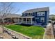 A beautiful blue two-story home with a lush green lawn, covered porch, and rock garden in the backyard at 18315 W 83Rd Dr, Arvada, CO 80007