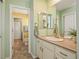 Bright bathroom featuring a sink with white cabinets, mirrors, and a doorway to a separate toilet area at 18315 W 83Rd Dr, Arvada, CO 80007