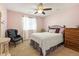 Comfortable bedroom featuring soft pink walls, a cozy bed, ceiling fan and ample natural light from the window at 18315 W 83Rd Dr, Arvada, CO 80007
