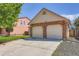 Attached two-car garage with brick accents, a paved driveway, and landscaping at 4548 Gibraltar Way, Denver, CO 80249