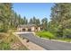 Sprawling ranch-style home with a three-car garage, stone accents, and private drive surrounded by lush trees at 8280 Bannock Dr, Larkspur, CO 80118