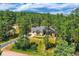 Landscaped front yard featuring a grand home with a large driveway, complemented by surrounding trees at 8280 Bannock Dr, Larkspur, CO 80118