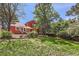 Backyard view with red siding and patio pergola, and grass yard at 7445 Shoreham Pl, Castle Pines, CO 80108