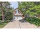 Inviting two-story home with a two-car garage, landscaped front yard, and mature trees at 7445 Shoreham Pl, Castle Pines, CO 80108