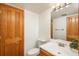 Cozy bathroom features a wood vanity, toilet, and mirror with decorative lighting, with a wooden door at 8745 Yukon St # 30, Arvada, CO 80005