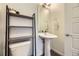 Contemporary half bathroom features a sleek pedestal sink, open shelving, and minimalist design at 10117 Morrison Rd, Lakewood, CO 80227