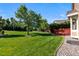 Expansive backyard featuring lush green lawn, mature trees, and a wooden deck, perfect for outdoor activities at 9561 Silver Hill Cir, Lone Tree, CO 80124