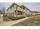 Two-story exterior elevation with light yellow siding, stone accents, and a well-maintained landscape at 16828 E Gunnison Dr # 7H, Aurora, CO 80017