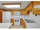 Bright kitchen featuring white appliances, wood cabinets, and a double basin sink at 14001 E Marina Dr # 607, Aurora, CO 80014