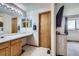 Bathroom with a long vanity, decorative mirror, and a door to the Primary bedroom at 11357 Iola St, Commerce City, CO 80640