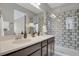Bathroom featuring double sinks, quartz countertops, and a shower with decorative tile at 23615 E 5Th Pl, Aurora, CO 80018