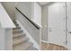 Carpeted stairs with contrasting wood railing and a white door at the base, leading upstairs at 23615 E 5Th Pl, Aurora, CO 80018