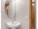 Stylish bathroom featuring a pedestal sink, a round mirror, and a wooden door at 5857 S Zante Cir, Aurora, CO 80015