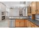 Bright kitchen with wooden cabinetry, stainless steel dishwasher, and view to staircase at 5857 S Zante Cir, Aurora, CO 80015