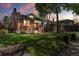 Dusk view of a charming brick home featuring a well-maintained lawn and mature trees, creating a warm, inviting atmosphere at 1260 S Emerson St, Denver, CO 80210