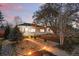 Charming home with a beautifully landscaped front yard, stone pathway, and flowering trees at dusk at 1711 Spruce St, Denver, CO 80220