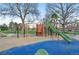 A colorful community playground with climbing structures, slides, and swings amidst mature trees at 1711 Spruce St, Denver, CO 80220