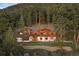 Aerial view of a luxury mountain home surrounded by lush forests, featuring a wrap around deck at 4560 Hilltop Rd, Evergreen, CO 80439