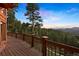 Spacious wood deck overlooking the lush forest and mountain views under a blue sky at 4560 Hilltop Rd, Evergreen, CO 80439
