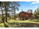 Log home with a large deck surrounded by trees in a natural setting at 4560 Hilltop Rd, Evergreen, CO 80439