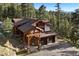 Exterior of home featuring log beams, stone accents, attached garage and a covered entryway at 4560 Hilltop Rd, Evergreen, CO 80439