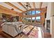 Open-concept living room featuring log beams, mountain views and a stone fireplace at 4560 Hilltop Rd, Evergreen, CO 80439