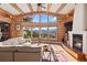 Open-concept living room with exposed log beams, stone fireplace, and large windows offering mountain views at 4560 Hilltop Rd, Evergreen, CO 80439